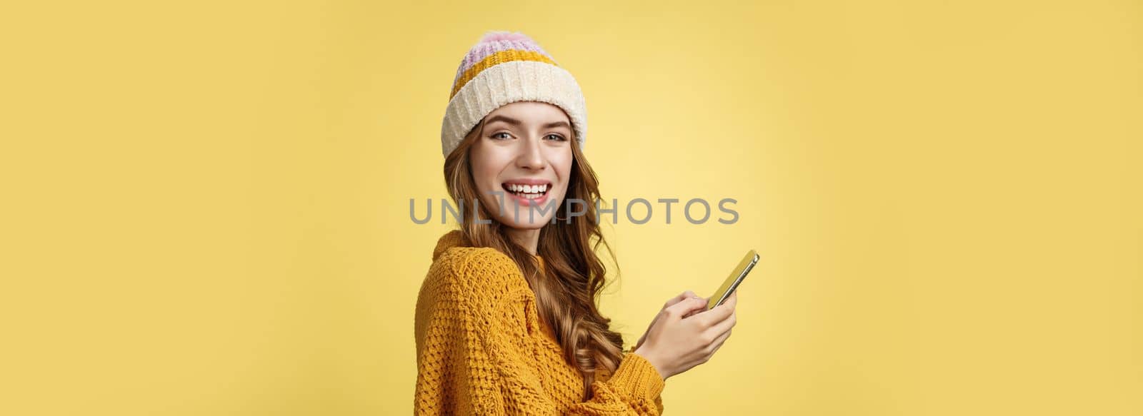 Profile shot entertained charming young woman playing mobile phone holding smartphone turning camera delighted having fun using cool app editing pics travel blogger messaging posting online by Benzoix