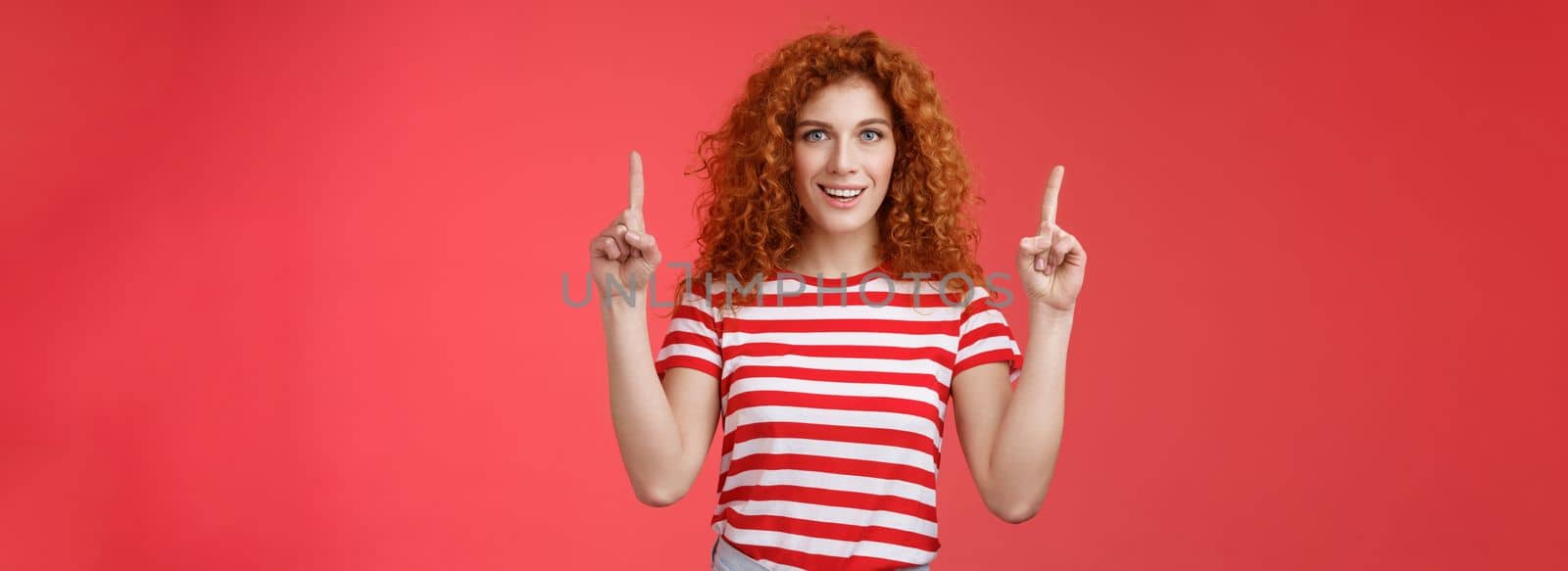 Lifestyle. Excited good-looking cheeky redhead ginger girl curly natural hair pointing raised index fingers up smiling impressed thrilled advising store directing promo advertising awesome haircare product.