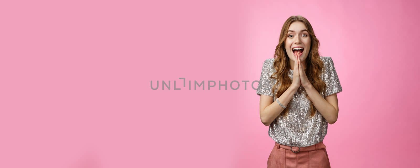 Excited attractive girlfriend eager start pack ready travel abroad win tickets press palms together happily thrilled looking amused feeling happiness standing pink background glamour outfit.