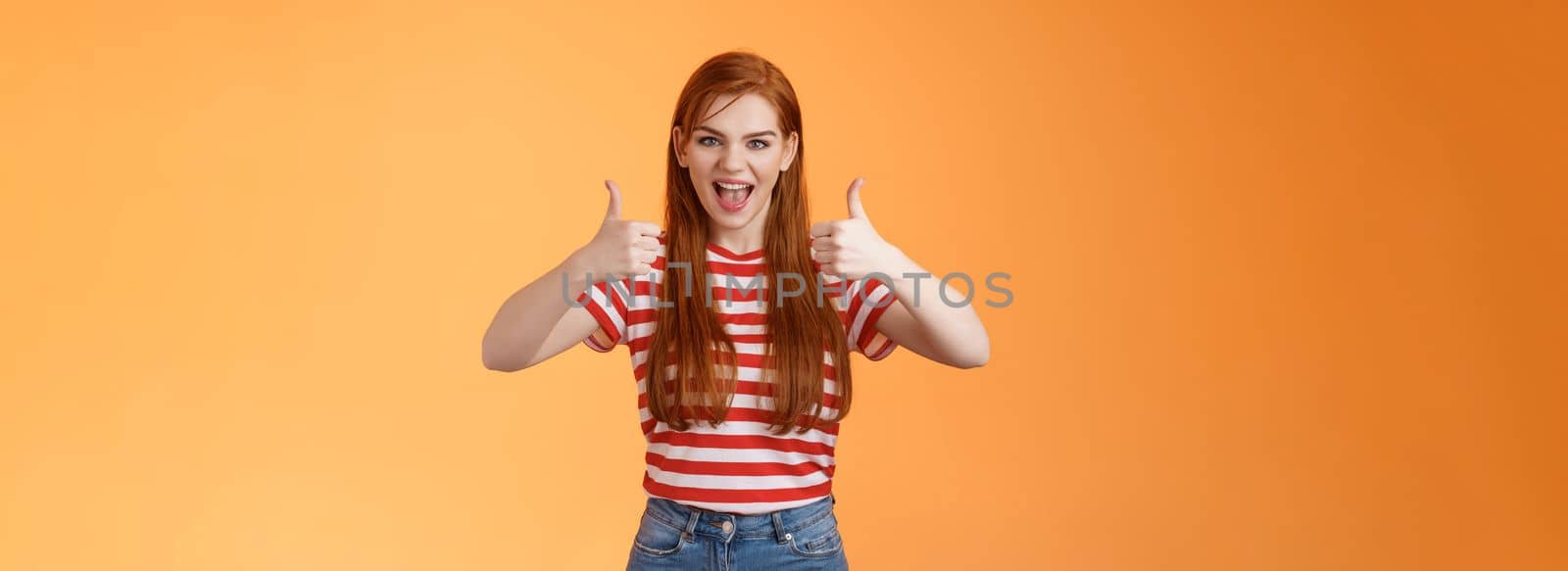 Sassy rebellious wild redhead cool girl having fun adore awesome party, show satisfactory gesture, thumb-up smiling say yeah joyfully, enjoy cool event, having fun, like idea, orange background.
