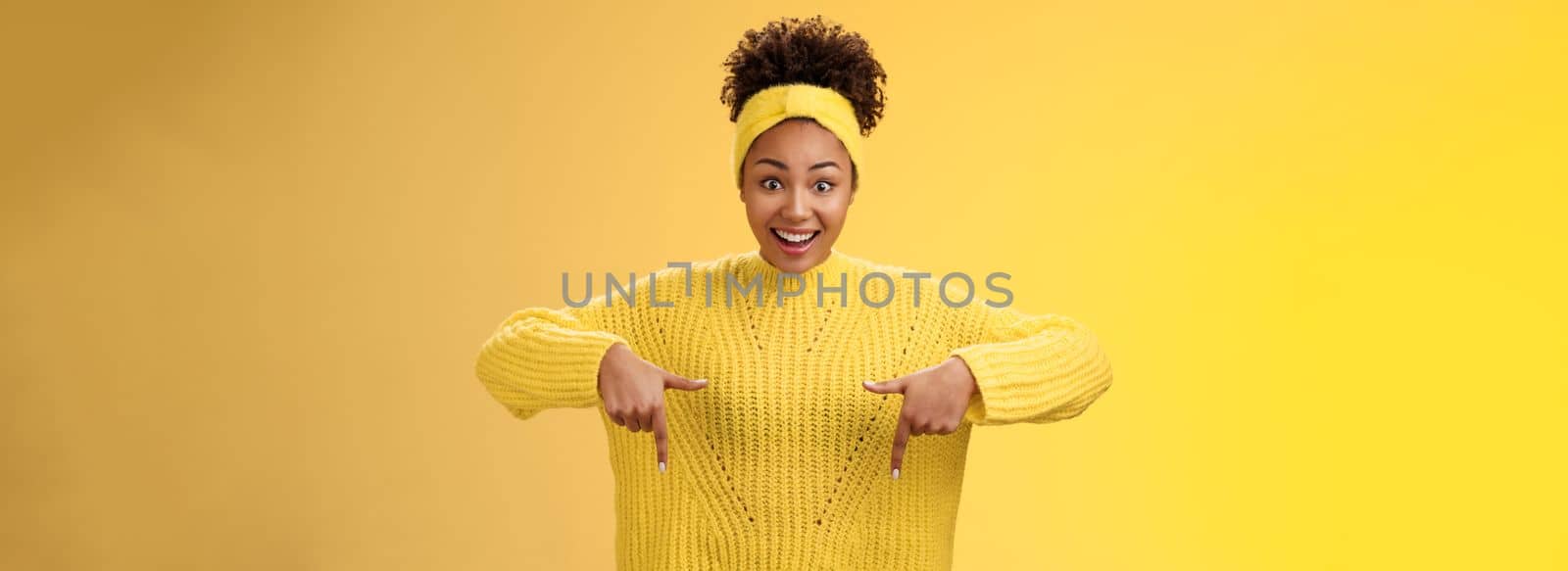 Enthusiastic impressed surprised beautiful african-american woman widen eyes drop jaw smiling gasping astonished pointing down amused standing yellow background showing amazing opportunity by Benzoix