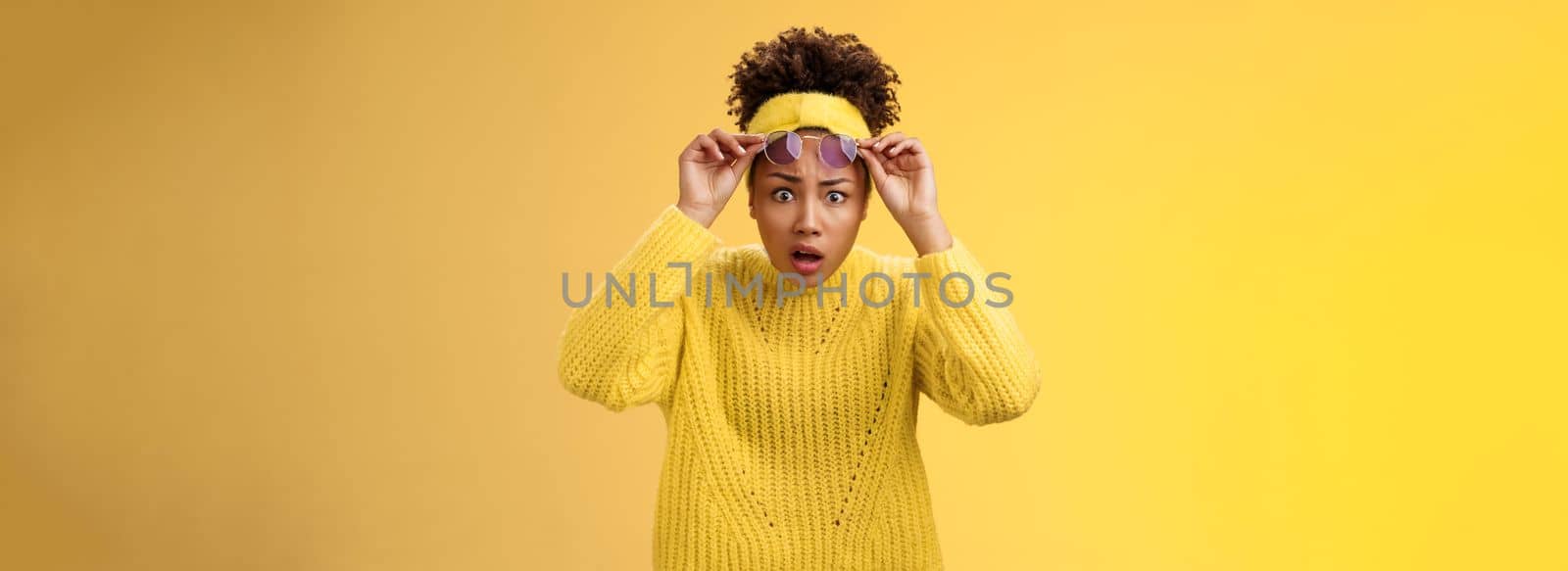 What heck. Shocked stunned confused african-american stylish modern girl in sweater headband take-off sunglasses widen eyes surprise speechless gasping look questioned freak-out, yellow background.