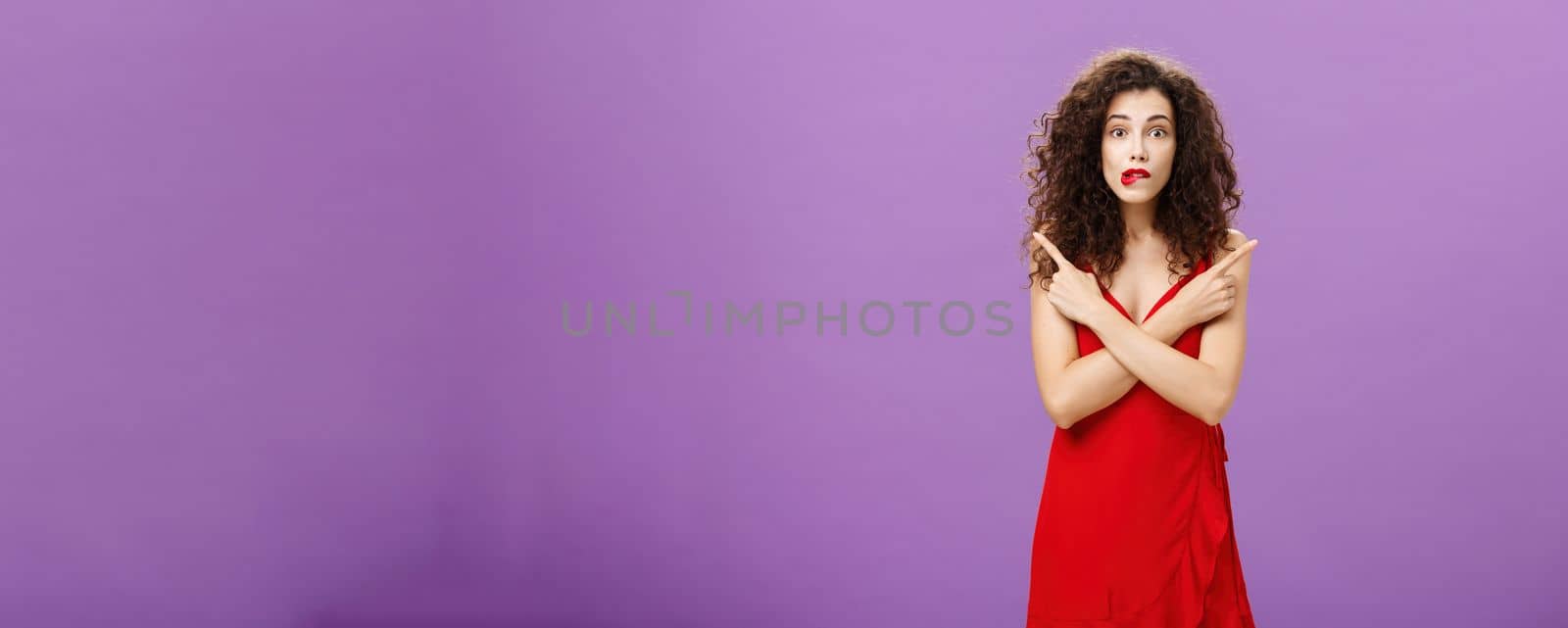 Enthusiastic unsure emotive elegant woman in stylish evening red dress biting lip looking excited pointing in different directions left and right being uncertain and doubtful in making decision by Benzoix