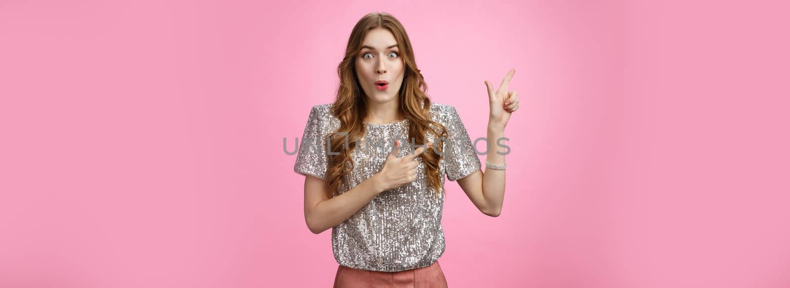 Attractive young girlfriend retelling incredible gossip spread party folding lips wow sound pointing upper left corner amused thrilled standing impressed pink background, lose speech awesome promo.