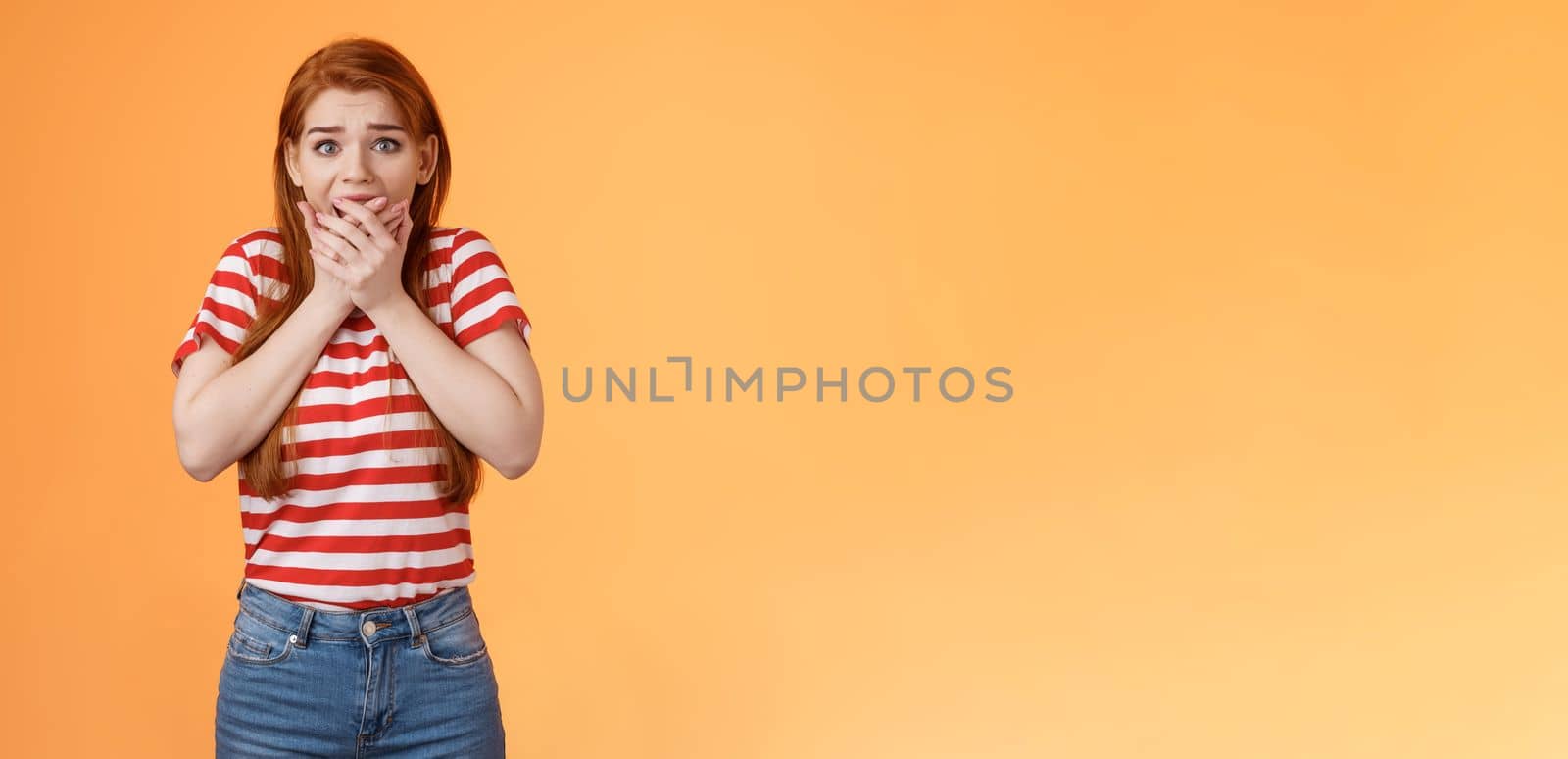 Scared speechless innocent female victim losing speech, press hands mouth shocked terrified stare camera frightened, trembling from fear, see someone commiting crime, insecure orange background.