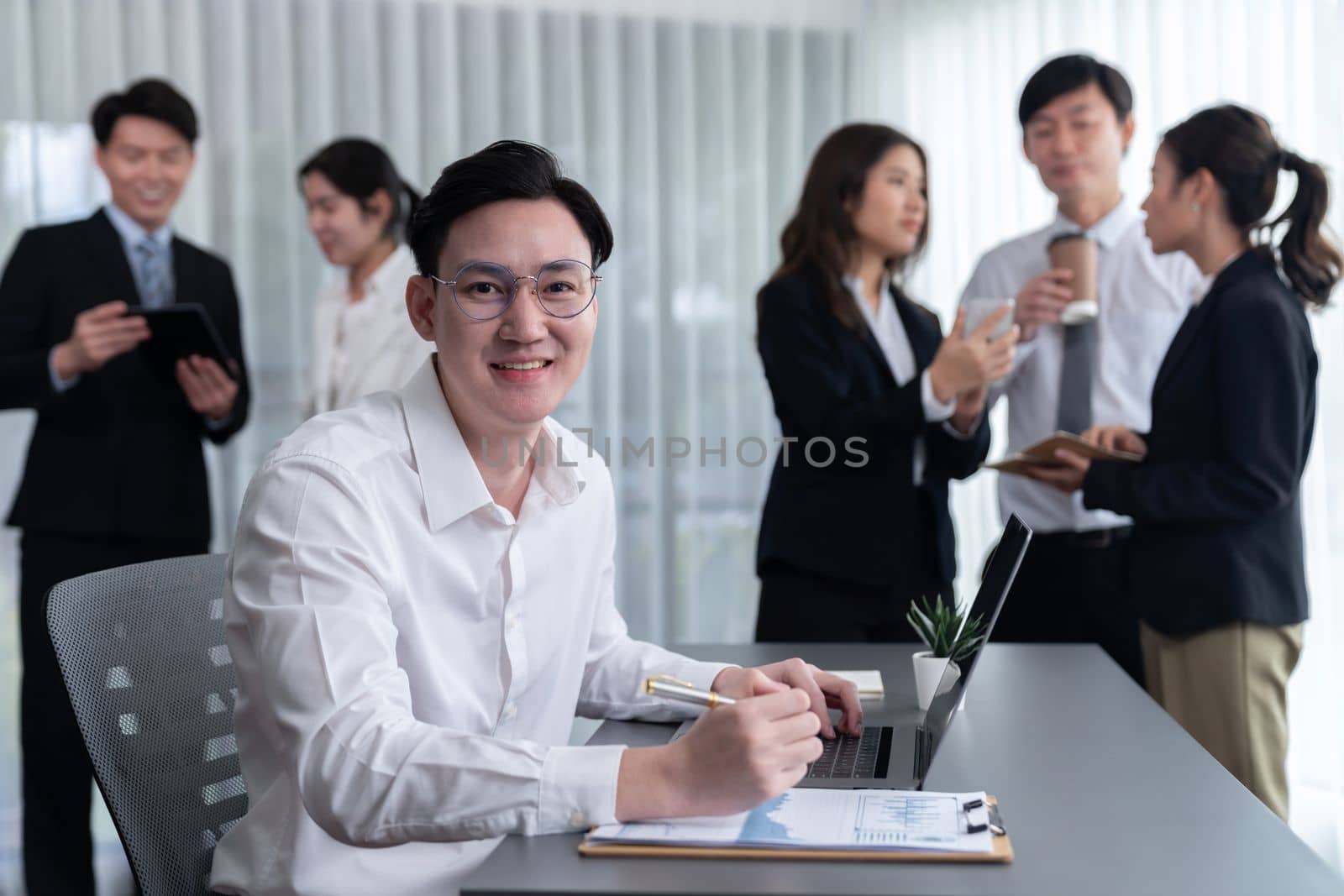 Portrait of focus young successful confident male manager, executive wearing business wear in harmony office arm crossed with blurred meeting background of colleagues, office worker.