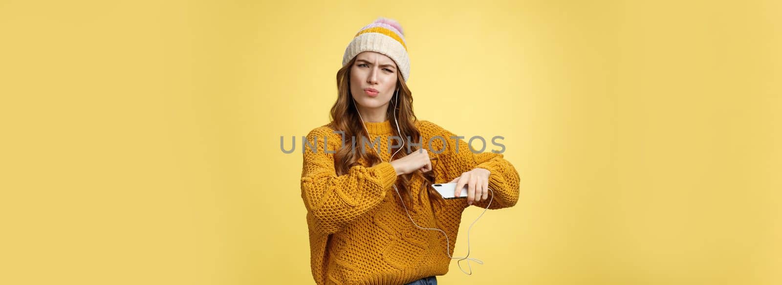 Shake your body. Portrait cool amused good-looking stylish girlfriend listen music via wired earphones dancing moving hands rhythm cool song holding smartphone folding lips frowning satisfied.