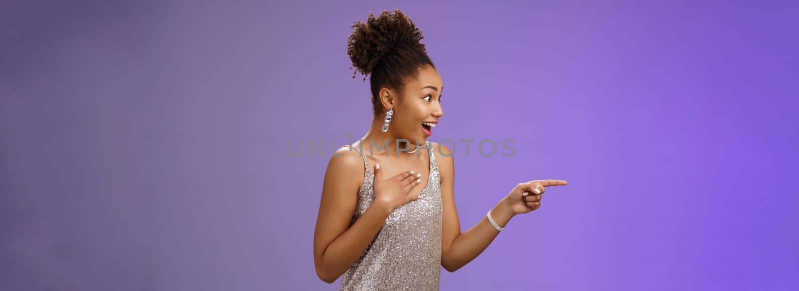 Impressed speechless thrilled elegant young african-american woman see celebrity press palm chest heartbeat fast pointing looking left amused astonished standing blue background amazed.