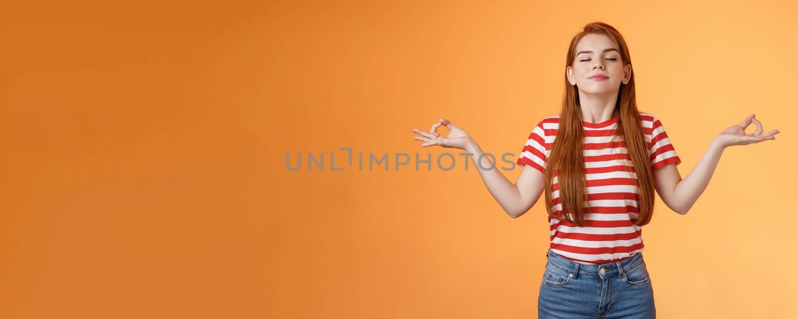 Girl listening relaxing podcast meditating indoors, breath fresh air, close eyes smiling peaceful delighted, stand orange background, chill carefree, enjoy practive yoga, relieve from stress.
