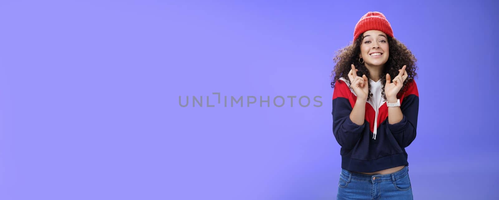 Dreamy optimistic woman praying friend will win standing supportive and excited smiling hopeful crossing fingers god good luck, waiting for miracle and dream come true posing against blue background by Benzoix