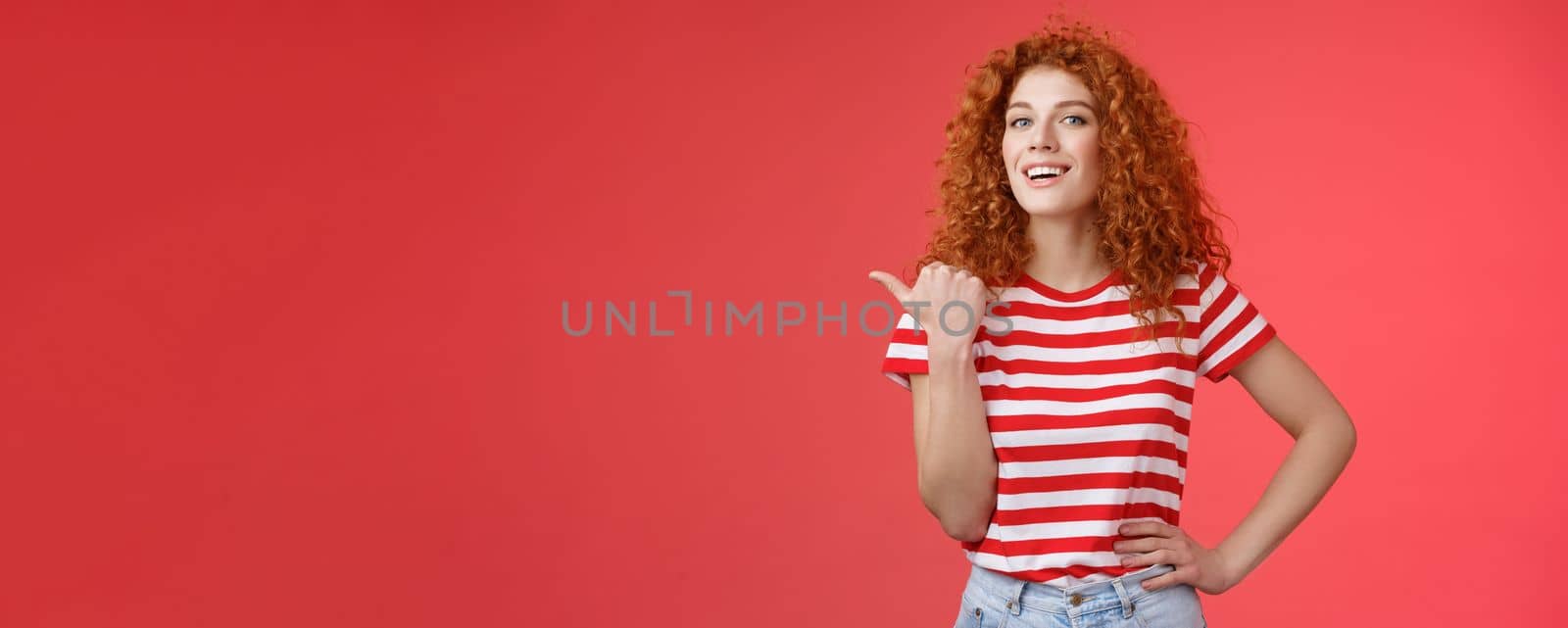 Accomplished good-looking redhead curly woman raise head proudly confident pointing thumb left smiling camera assertive sharing awesome product location recommend perfect store offer.