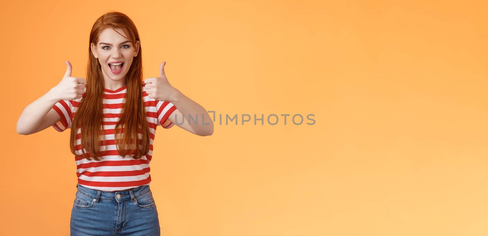 Sassy rebellious wild redhead cool girl having fun adore awesome party, show satisfactory gesture, thumb-up smiling say yeah joyfully, enjoy cool event, having fun, like idea, orange background.