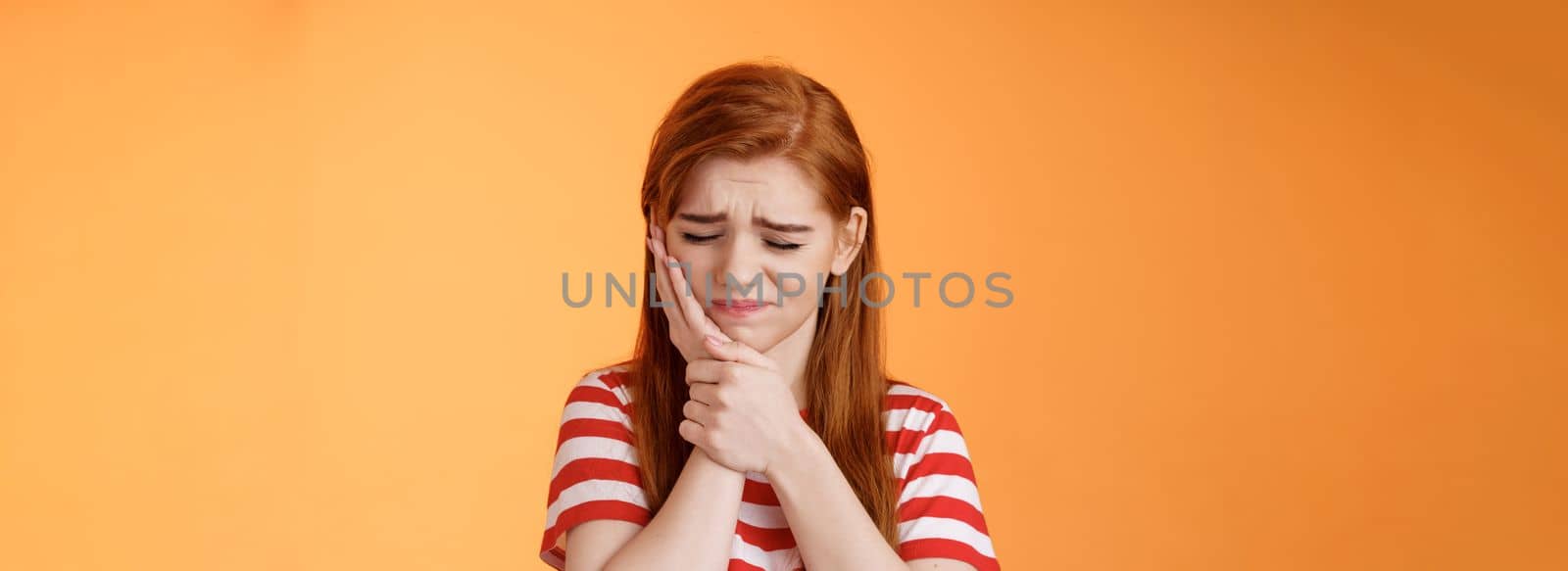 Close-up upset cute uneasy redhead girl suffer toothache, hold hand cheek frowning, close eyes awful tooth pain, have rotten teeth, decay problems, make dentist appointment, wait dental clinic by Benzoix