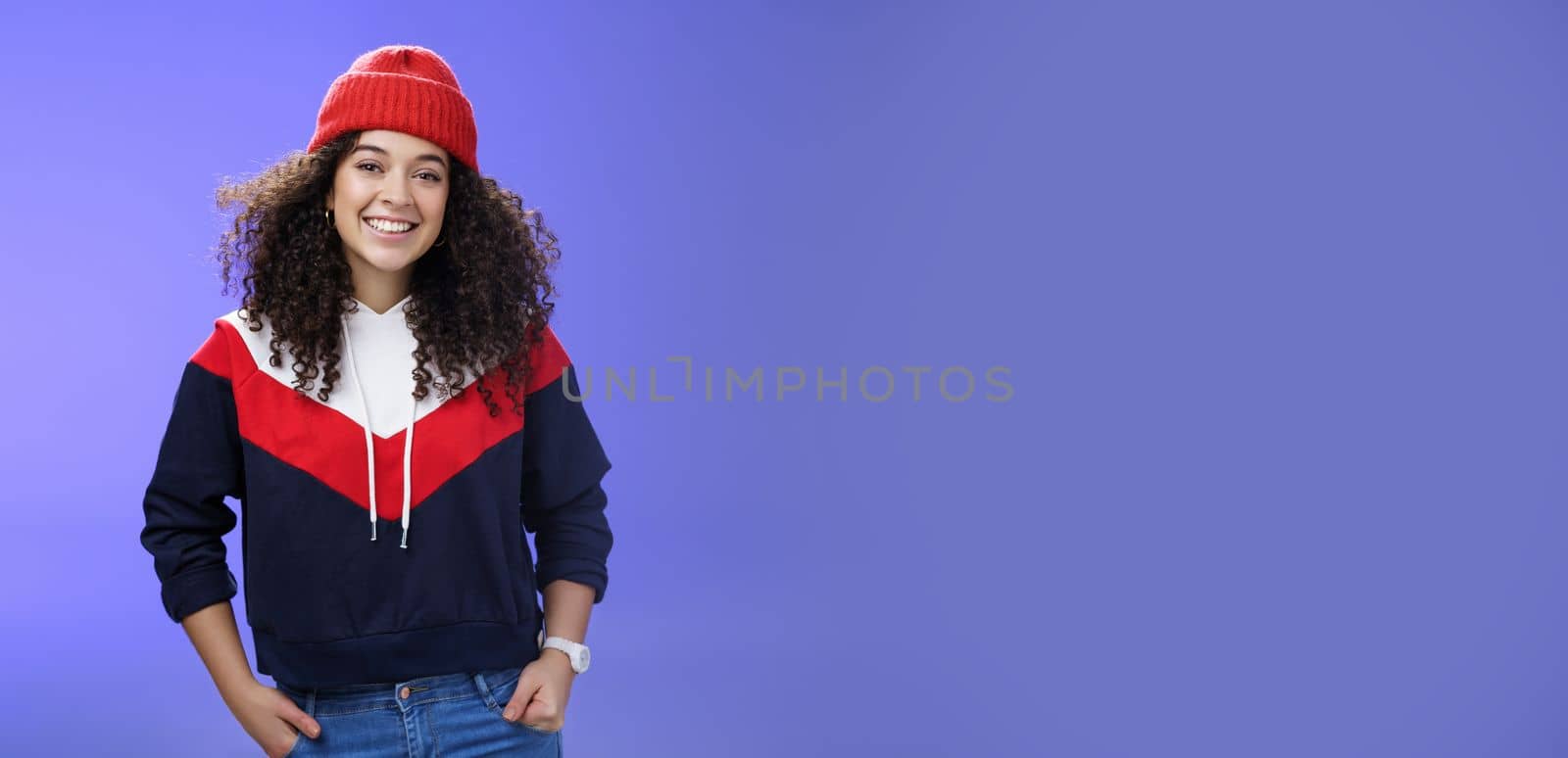 Girl invites join her team to srow snowballs. Portrait of friendly-looking carefree joyful woman with curly hair in red cute beanie and warm sweatshirt smiling joyfully getting ready for winter by Benzoix