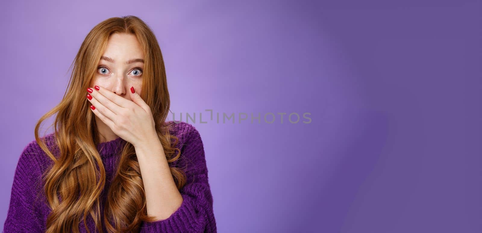 Lifestyle. Impressed speechless cute ginger girl hearing stunning gossip covering mouth form amazement and shook raising eyebrows wondered as reacting to unexpected revelation or rumor over purple background.