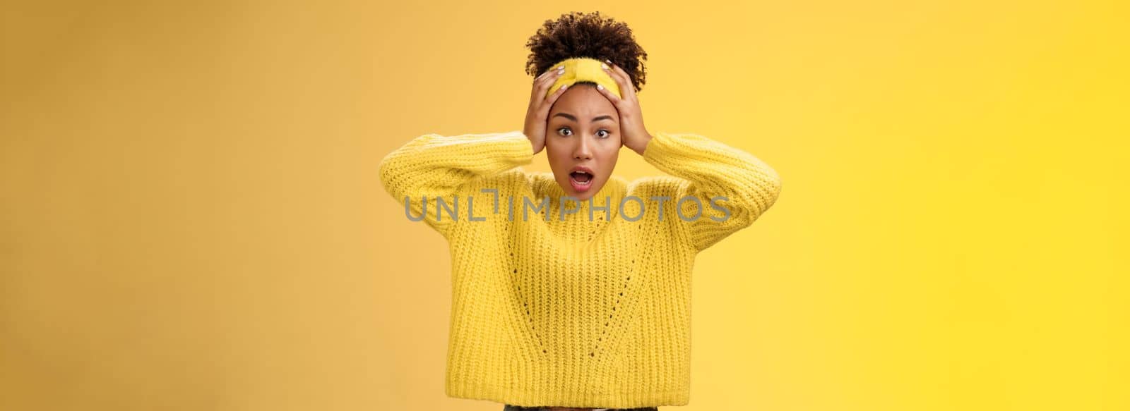 Concerned troubled surprised african-american woman gasping shocked hold head widen eyes perplexed face troublesome situation panic unaware what do, standing frustrated yellow background.