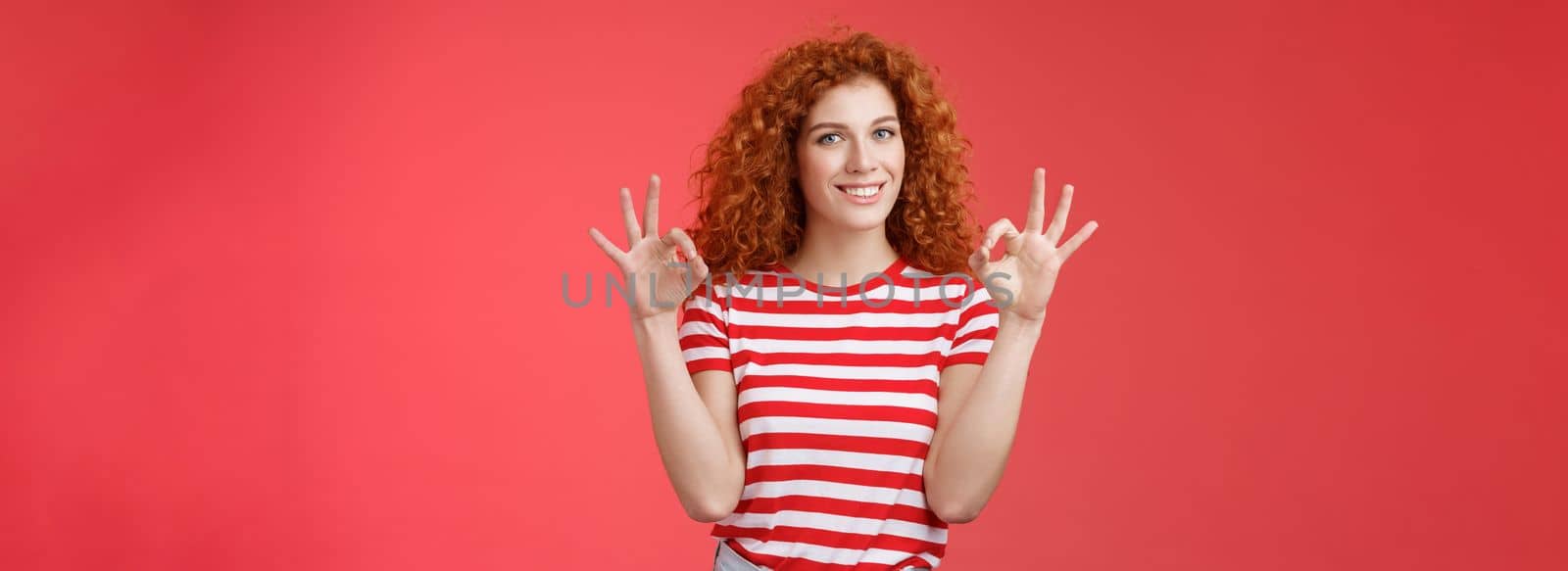 Fine relax everything perfect. Satisfied good-looking redhead cheerful sassy girlfriend curly haristyle show okay ok confirm gesture smiling approval agree good terms stand red background.