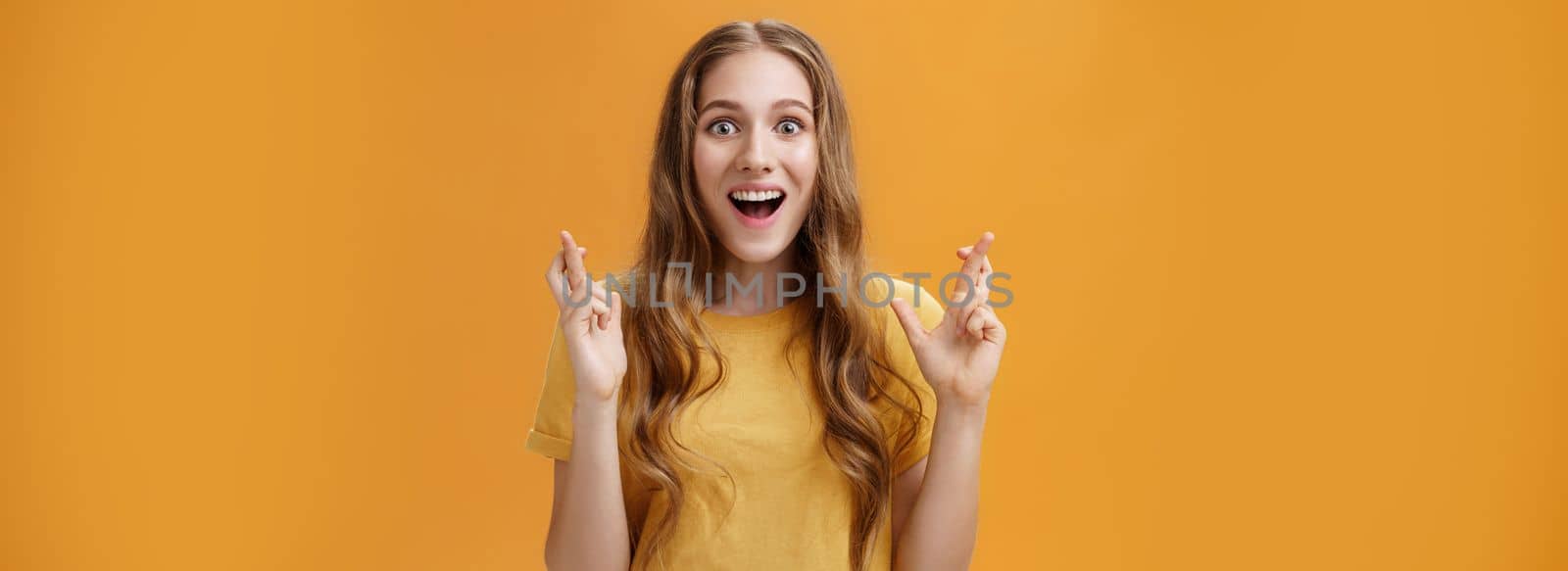 Lifestyle. Waist-up shot of interested amused and enthusiastic good-looking woman in casual t-shirt crossing fingers for good luck smiling amazed and delighted being happy and hopeful things will be well.