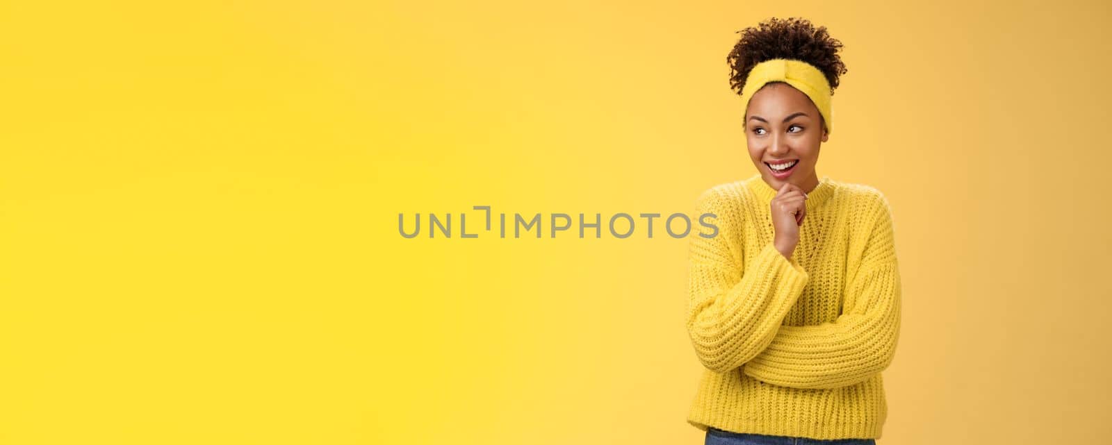 Impressed excited surprised happy attractive african-american curly-haired girl headband sweater giggling amazed look left touching chin thoughtful laughing funny scene, standing yellow background.