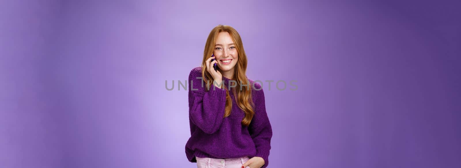 Girl likes talking on mobile phone with funny friend. Portrait of carefree charming redhead european woman with freckles holding mobile phone near ear as having conversation, laughing joyfully by Benzoix
