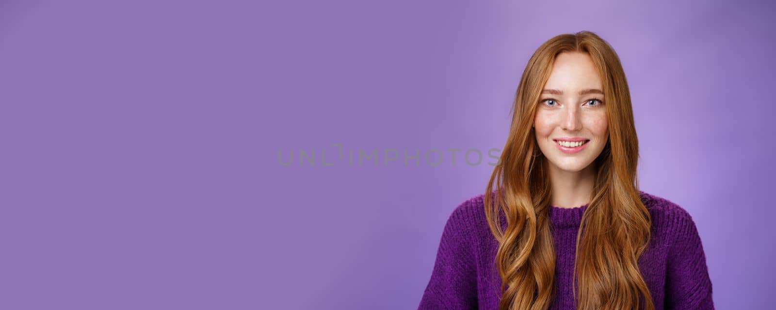 Lifestyle. Close-up shot of hopeful and optimistic happy young redhead 20s girl with freckles and long hair smiling joyfully with faith in eyes and prominent look posing against purple background.