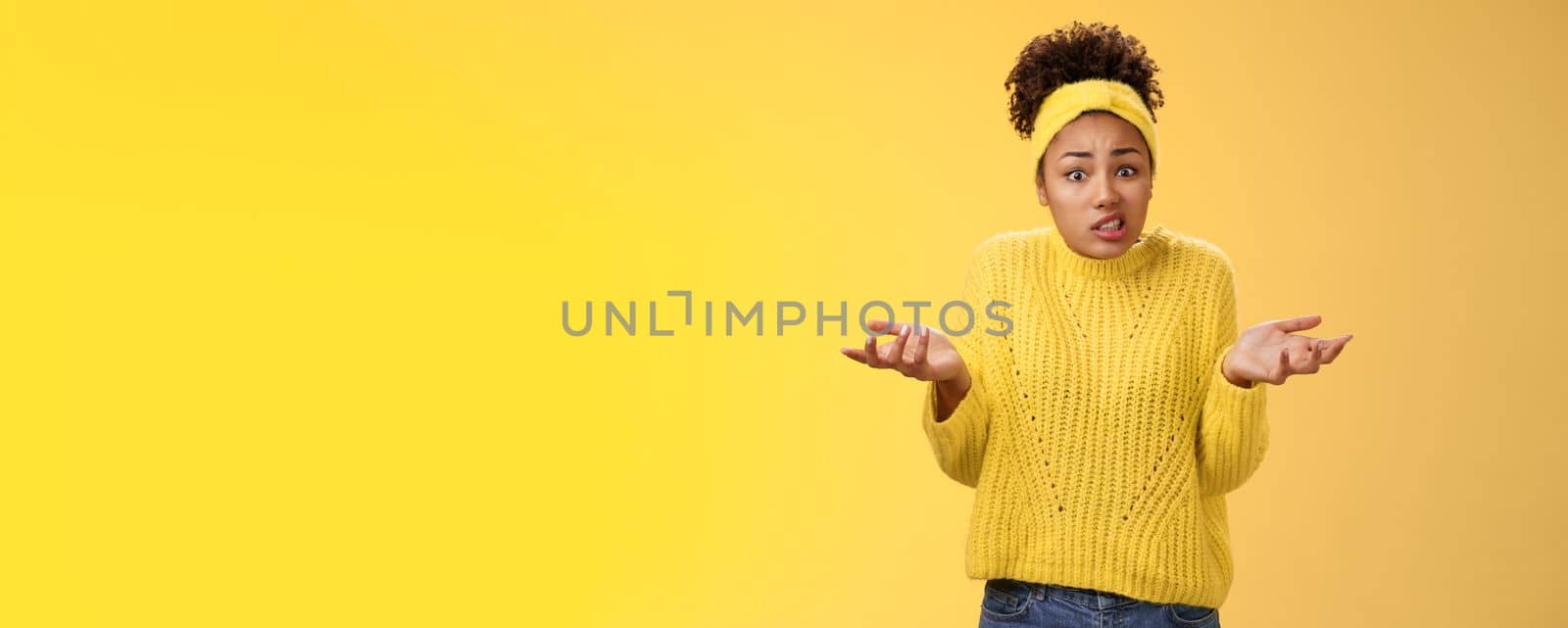 Confused awkward cute female employee messed-up papers lost paperwork shrugging raise hands uncertain say oops cringing uncomfortable standing clueless no idea what happening, yellow background.