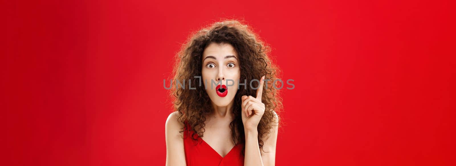Woman remembered important information feeling excited adding suggestion with raised index finger in eureka gesture, folding lips in raising eyebrows being thrilled finally understanding. Emotions and gestures concept