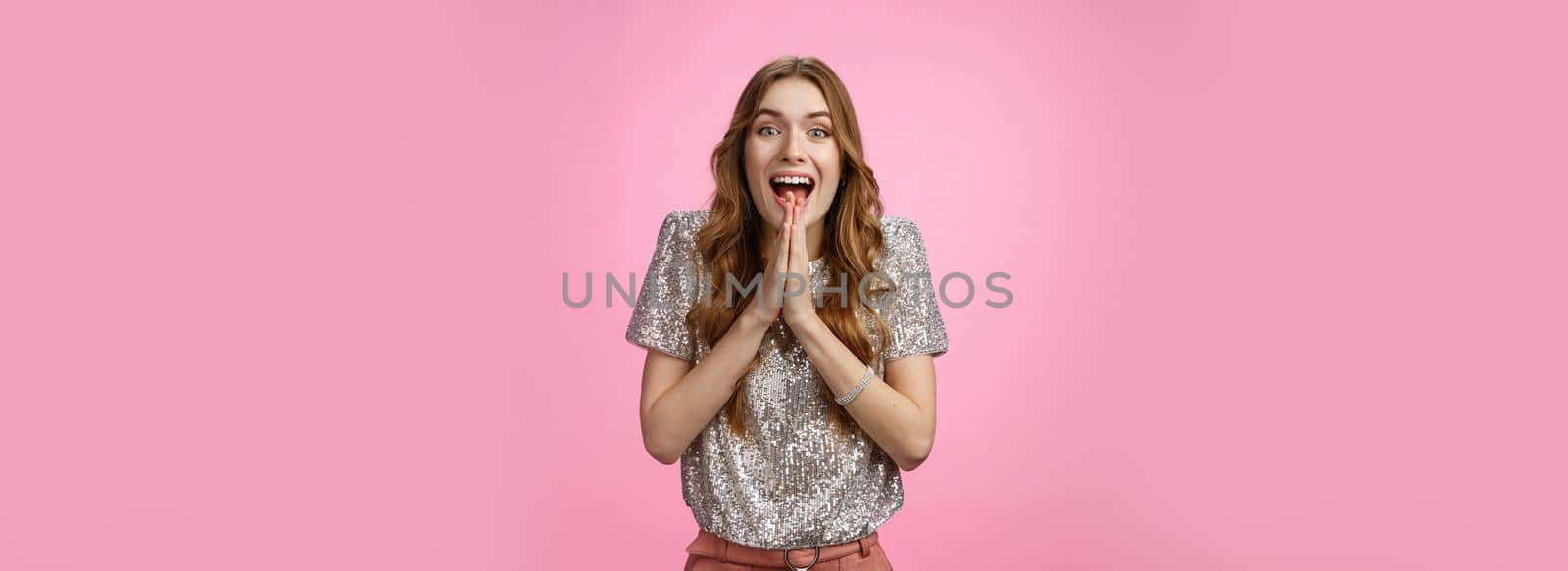 Excited attractive girlfriend eager start pack ready travel abroad win tickets press palms together happily thrilled looking amused feeling happiness standing pink background glamour outfit.