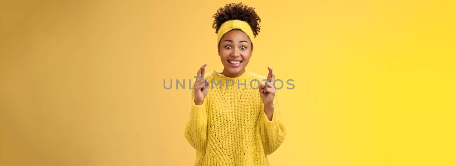 Excited optimistic hopeful young timid african-american girl. in yellow sweater smiling broadly thrilled anticipating good news bealive fortune cross fingers good luck grinning expect good news.