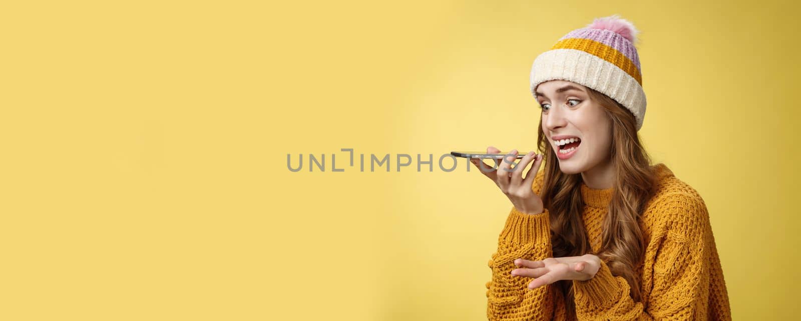 Close-up annoyed angry young woman shouting phone recording audio message irritated arguing having fight friend, raise hand dismay screaming freaked-out, yellow background. Copy space