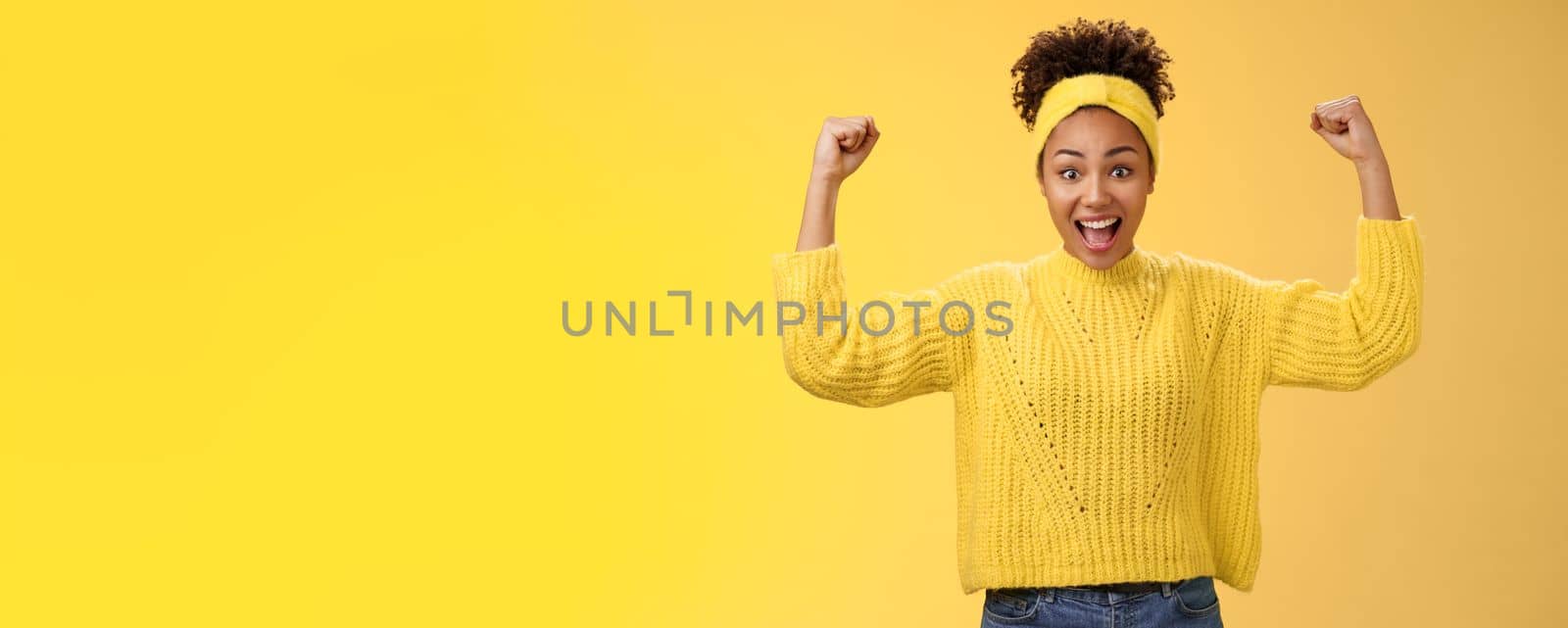 Proud impressed charming girlfriend encourage girlfriend win first place happy for friend rase fists celebration triumph gesture smiling broadly congratulation good work win, yellow background.