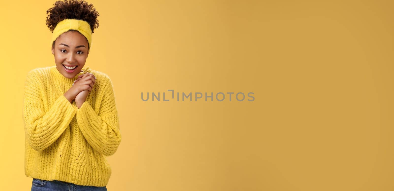 Touched tender african-american woman press palms together sighing happily smiling enjoying lovely scene grinning look passionate delighted grateful have united supportive family, yellow background.