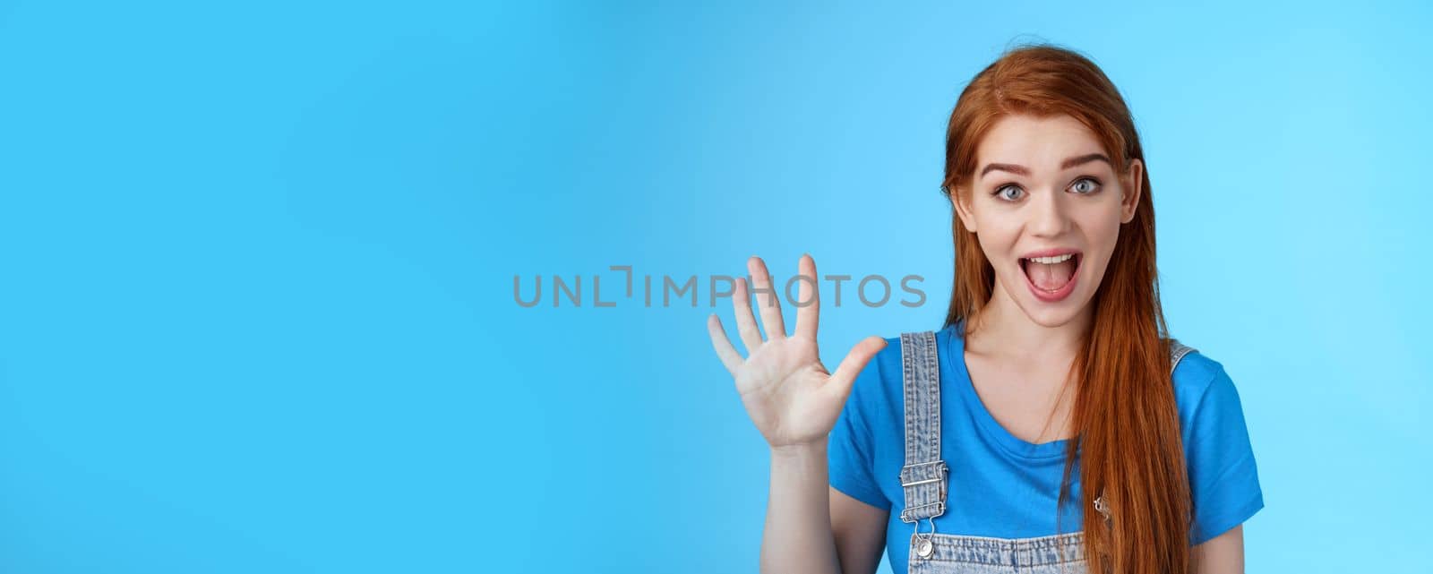 Cheerful amused redhead woman long natural red hairstyle show number five fifth, make order, counting fingers, smiling broadly, talking amused, count down, stand blue background joyful.