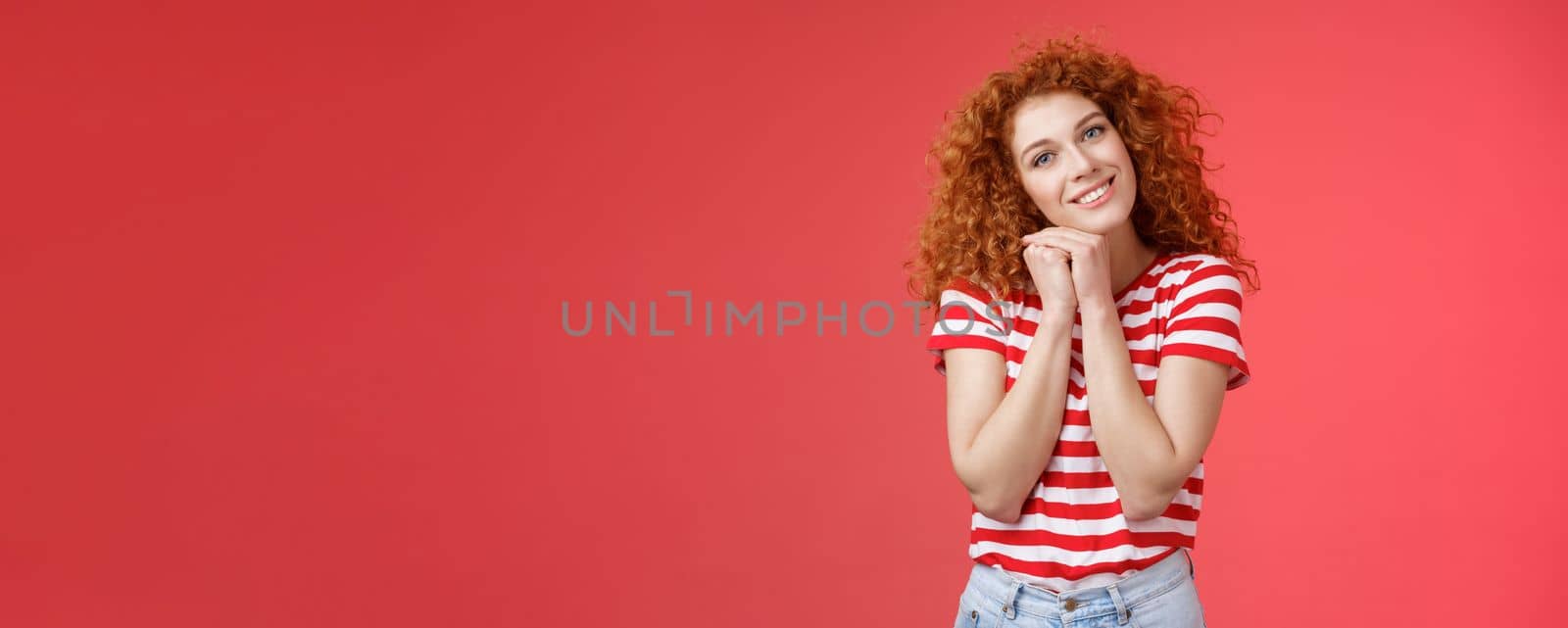 Tender feminine caring redhead curly-haired female romantic gaze camera tilt head clench palms near head silly lovely look smiling delighted cheerful dreamy sighing look with sympathy by Benzoix