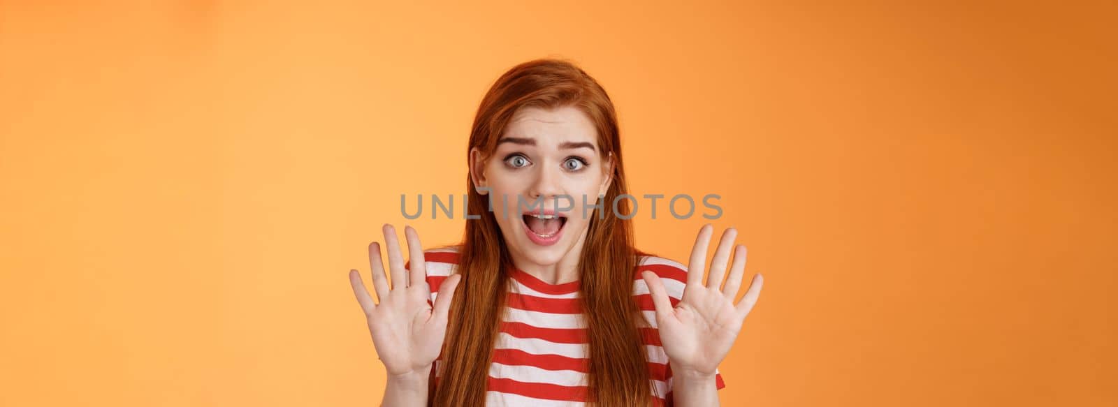 Shocked inssecure worried redhead woman plead not guilty, trying calm down angry customer, raise hands surrender innocent, open mouth, stare concerned camera, defend herself, explain situation.