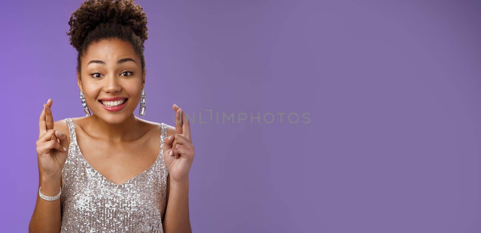 Cheerful optimistic charming african american girlfriend. supporting friend make wish wanna win first prize cross fingers luck smiling broadly wear glittering silver dress anticipating good fortune.