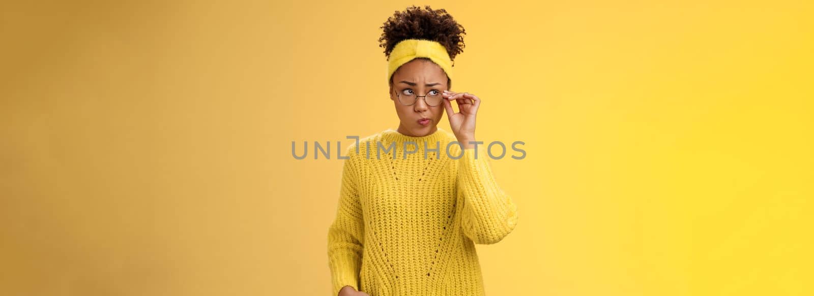 Unsure thoughtful hesitant cute african-american millennial teenage girl in round glasses sweater headband solving riddle mind look up doubtful touch eyewear smirking, thinking yellow background by Benzoix
