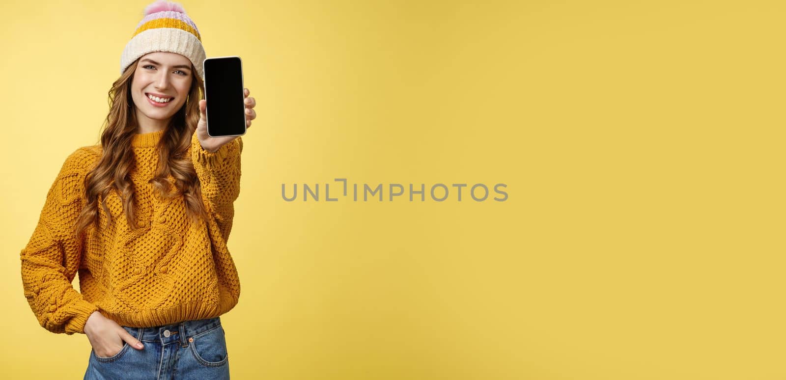 Charming outgoing smiling trendy girl extend arm showing you brand new smartphone, display grinning satisfied consulting friend what filter put using app edit photo mobile phone, yellow background.