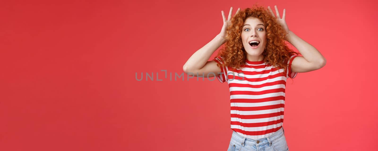 Lifestyle. Impressed excited shocked young cute redhead curly-haired ginger girlfriend reacting amazed surprised awesome gift cannot believe own eyes grab head thrilled open mouth ambushed red background.