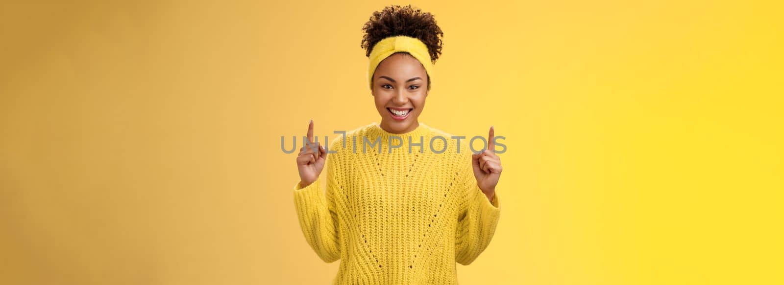 Excited charming young african-american girlfriend afro hairstyle in sweater headband pointing up index fingers smiling giggling asking buy boyfriend awesome cosmetics b-day present.