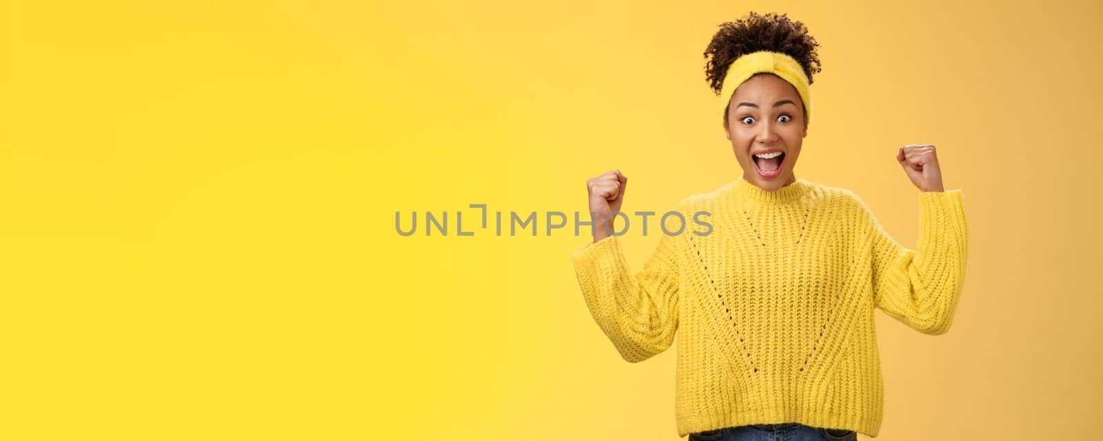 Yes finally prize mine. Excited surprised amused african-american girl celebrating victory achivement cheering smiling broadly yelling rest fists triumphing success, standing yellow background.
