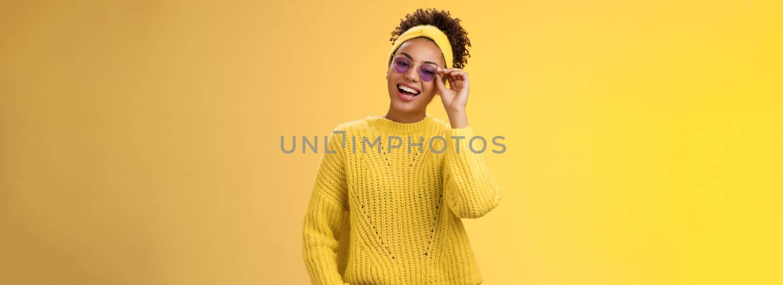 Stylish chill confident modern millennial teenage girl sweater headband blue sunglasses touching glasses frames smiling broadly assertive self-assured look grinning delighted hold hand pocket.
