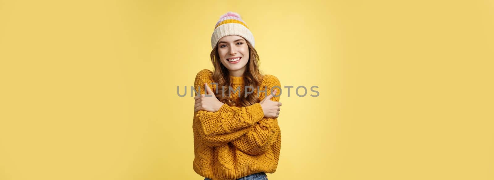 Getting cold bring jacket. Portrait charming tender feminine cute girlfriend embacing herself cuddling smiling warm gaze freezing outside standing knitted sweater hat, yellow background by Benzoix
