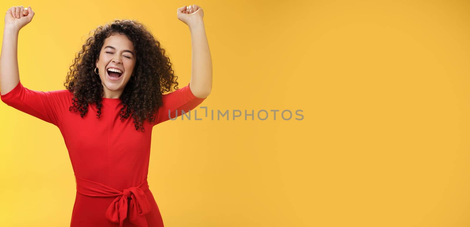 Oh yeah I am winner, on top of world. Excited ambitious and happy young successful busiensswoman getting promotion yelling yes with broad smile and closed eyes lifting hands in triumph and celebration.