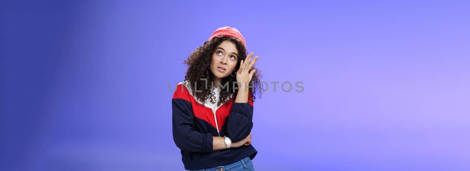 Waist-up shot of bored and annoyed assertive arrogant cool girl in streetstyle outfit rolling eyes up making facepalm and grimacing from irritation and disappointment, posing against blue background.
