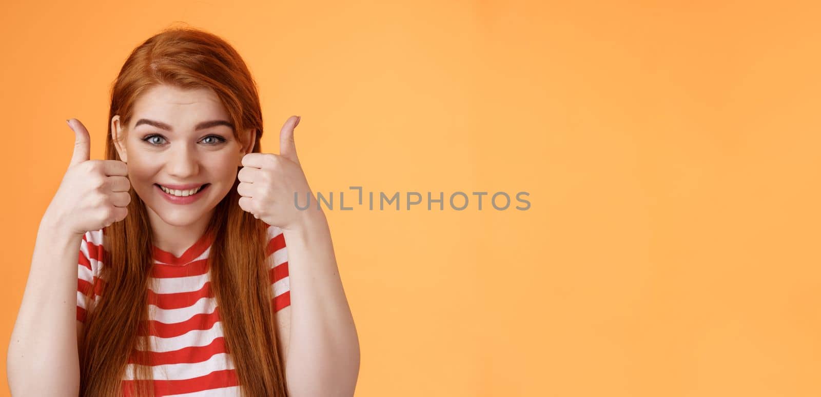 Hopeful cheerful cute redhead girlfriend rooting for you, believe win, smiling supportive satisfied, show thumbs-up delighted, approve choice, wish good luck, encourage friend, orange background.