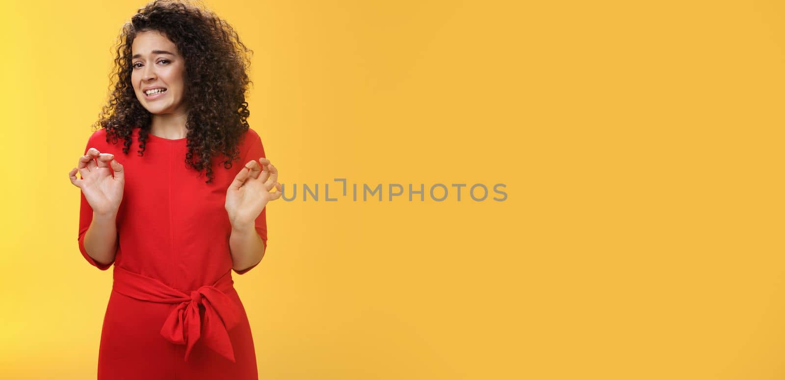 Girl hates washing dished grimacing from dislike and disgust wanting puke from aversion raising palms and stepping back frowning refusing displeasing offer over yellow background. Copy space