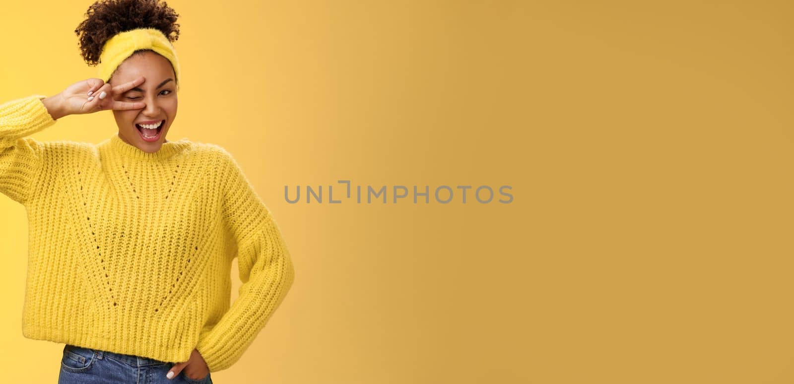 Friendly self-assured energetic african-american smiling healthy girl winking positive attitude grinning cheerful show peace victory lucky gesture hold hand waist confident, yellow background by Benzoix