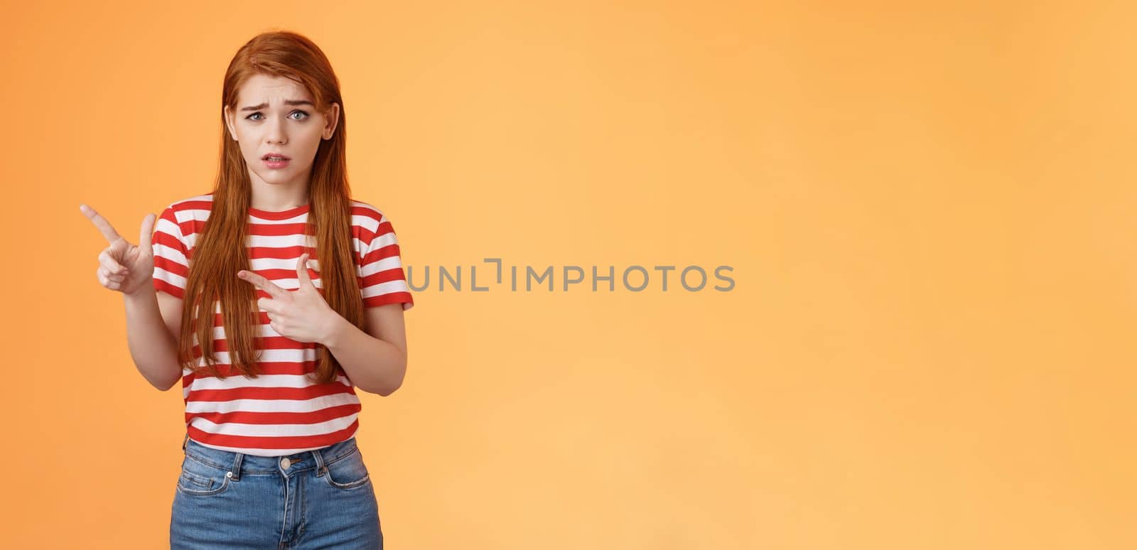 Insecure questioned frustrated cute redhead girl feel nervous unsure about suspicious offer frowning, grimacing doubtful and hesitant, pointing left look camera puzzled, asking question by Benzoix