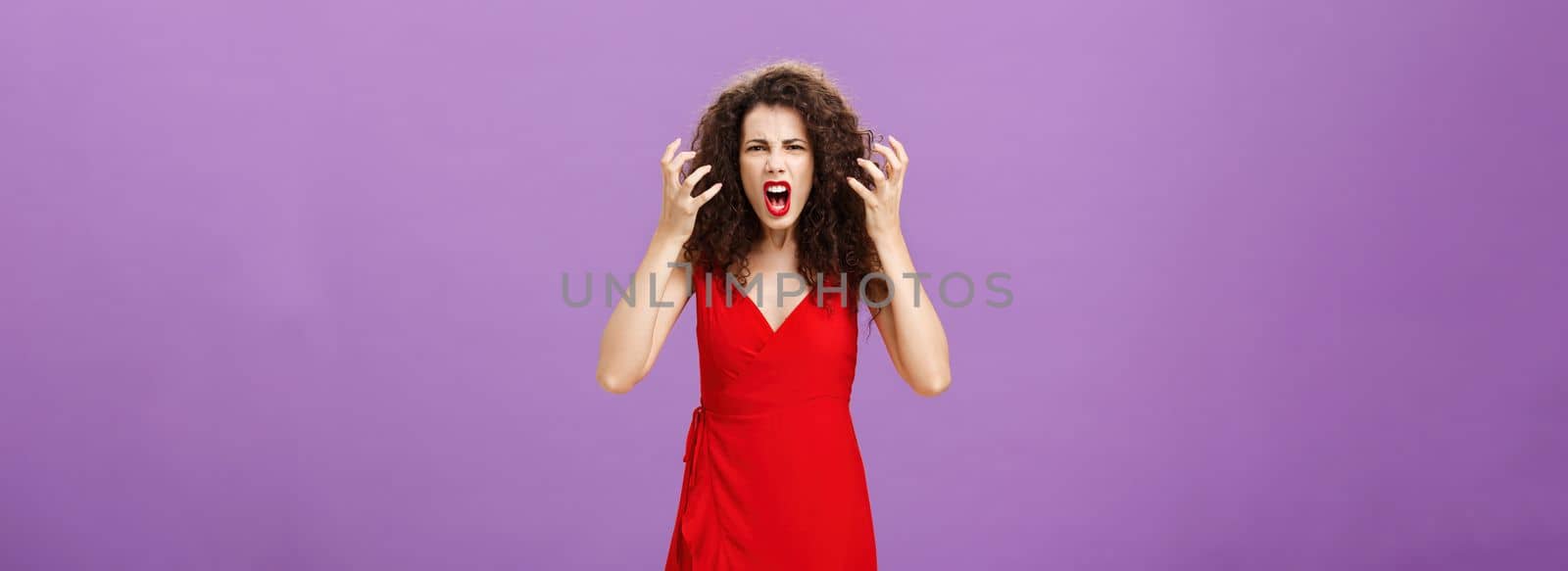 Woman getting annoyed and pissed employees spoiling her perfomance. Portrait of outraged furious female musician in red evening dress raising clenched fists grimacing and yelling angry. Copy space